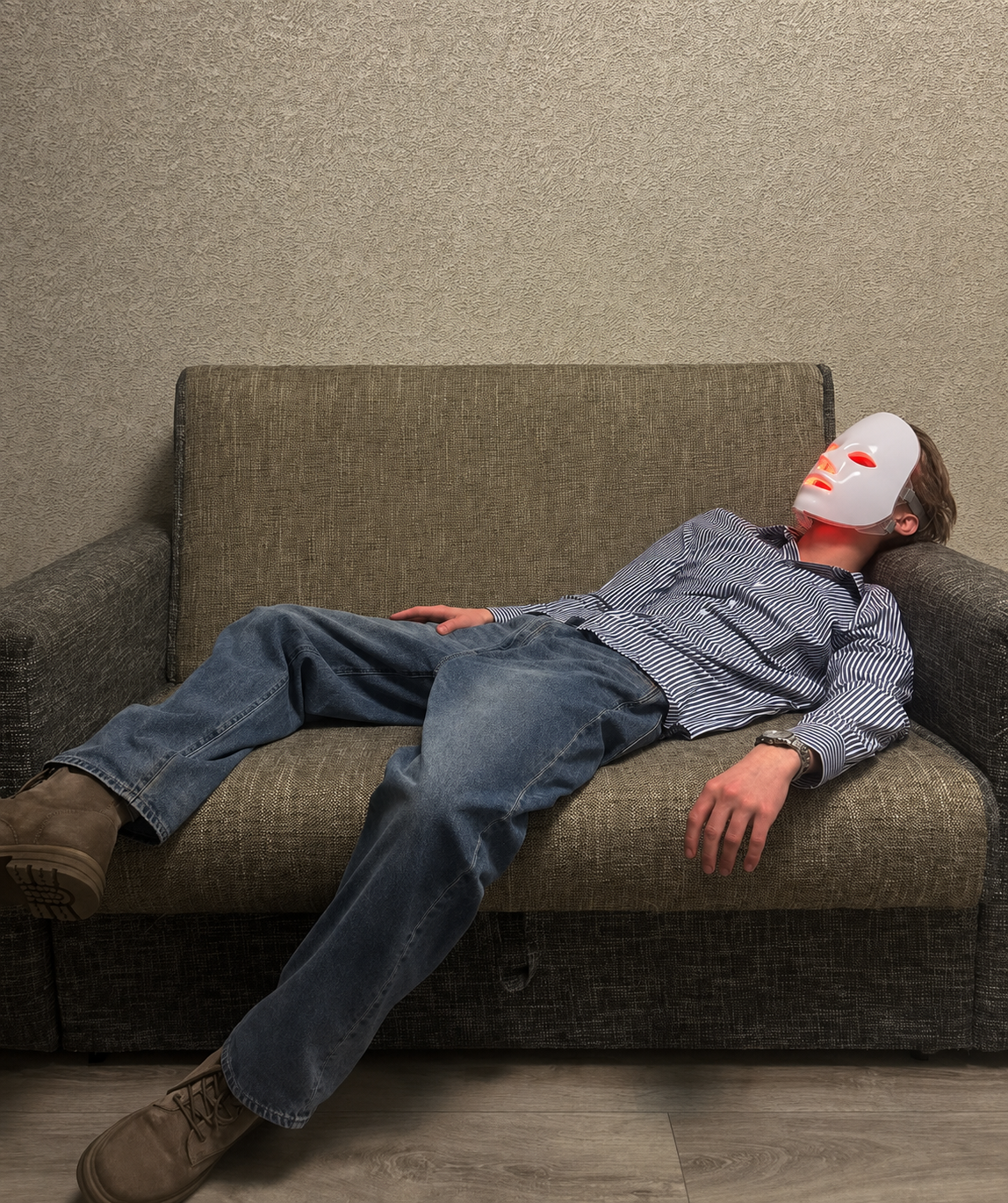 Adult man relaxing on a sofa while wearing the Light Mask Glow