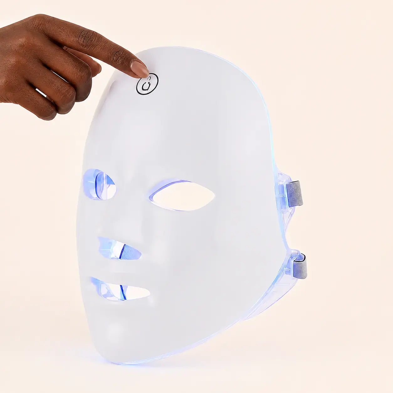 A Black hand touching the single control on The Light LED face mask